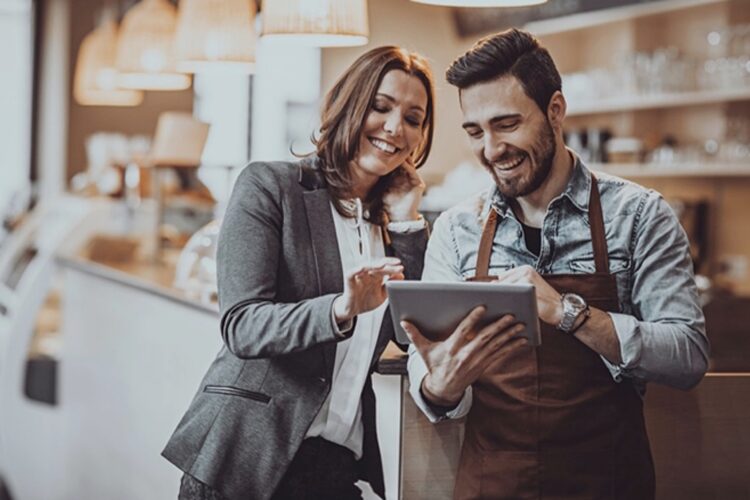 Manager and employee Smiling Looking At Tablet Device.