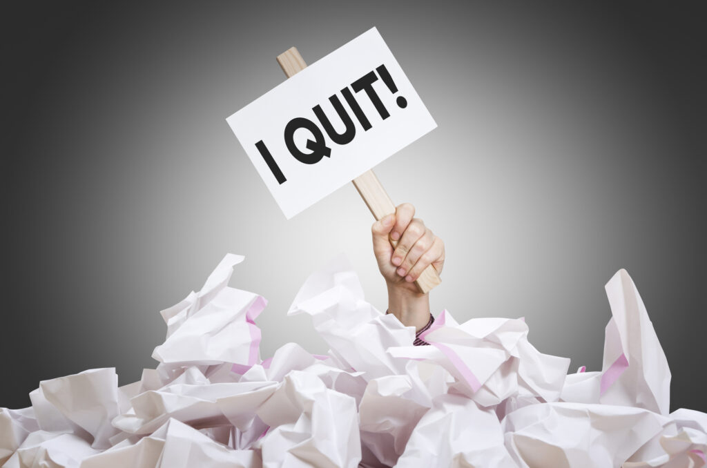 I quit! placard in hand with crumpled paper pile.