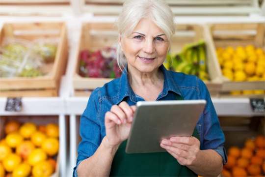 Grocery employee in produce section with tablet