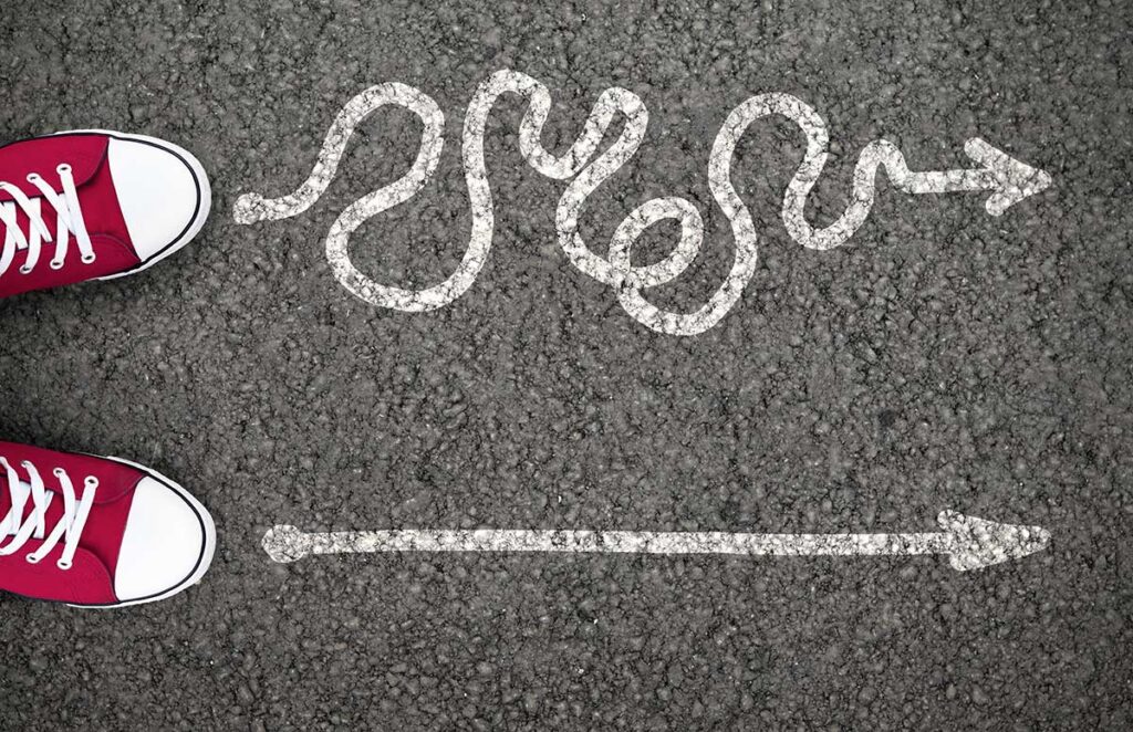 Two lines drawn in chalk on a road, one straight and one squiggly