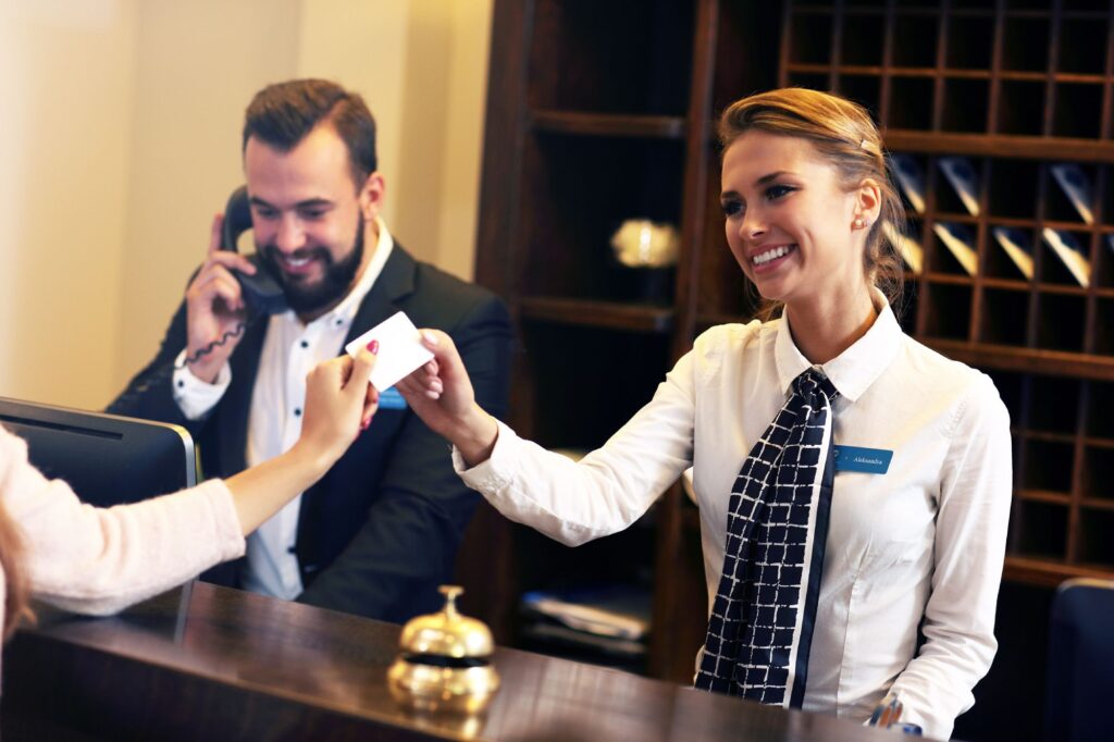 Guest getting key card at the front desk of hotel.