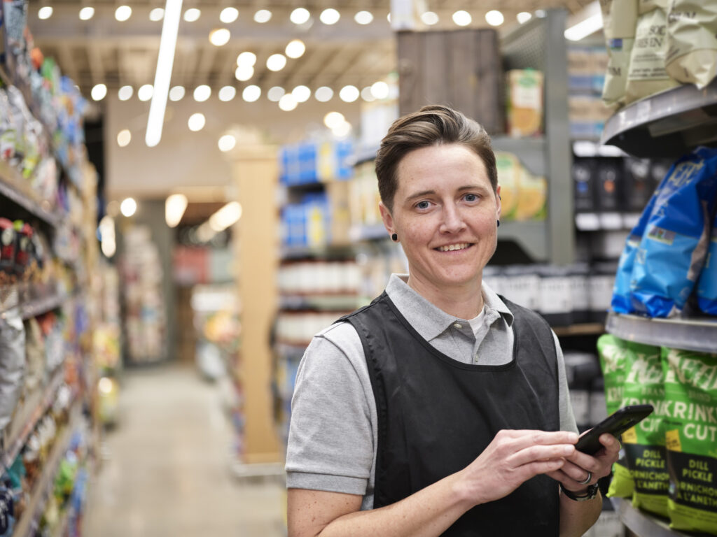 A grocery associate completes training content in the aisle of the store