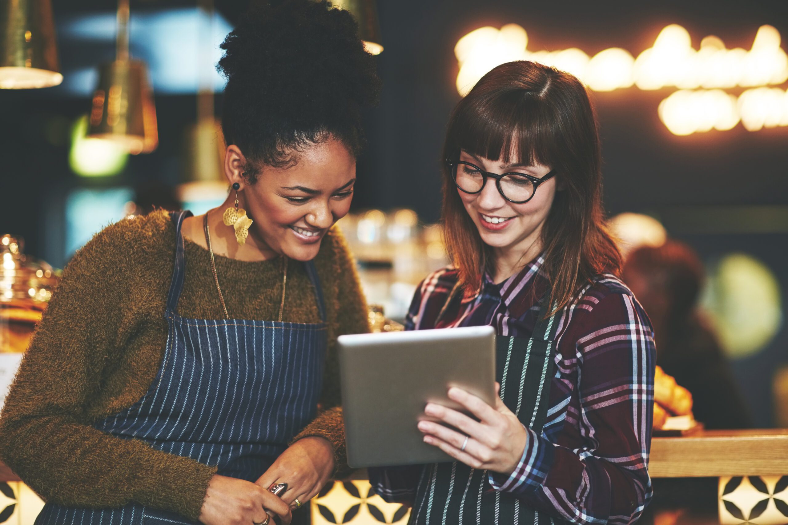 Shot of two young women using a digital tablet together while working at a coffee shop