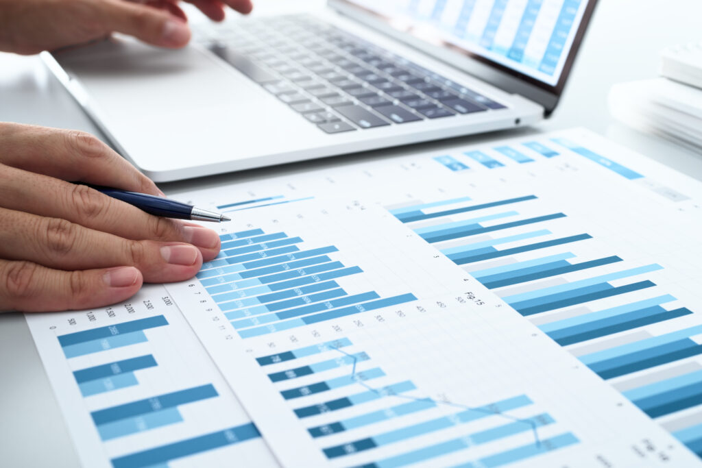 Man reviewing charts on reports and laptop display.