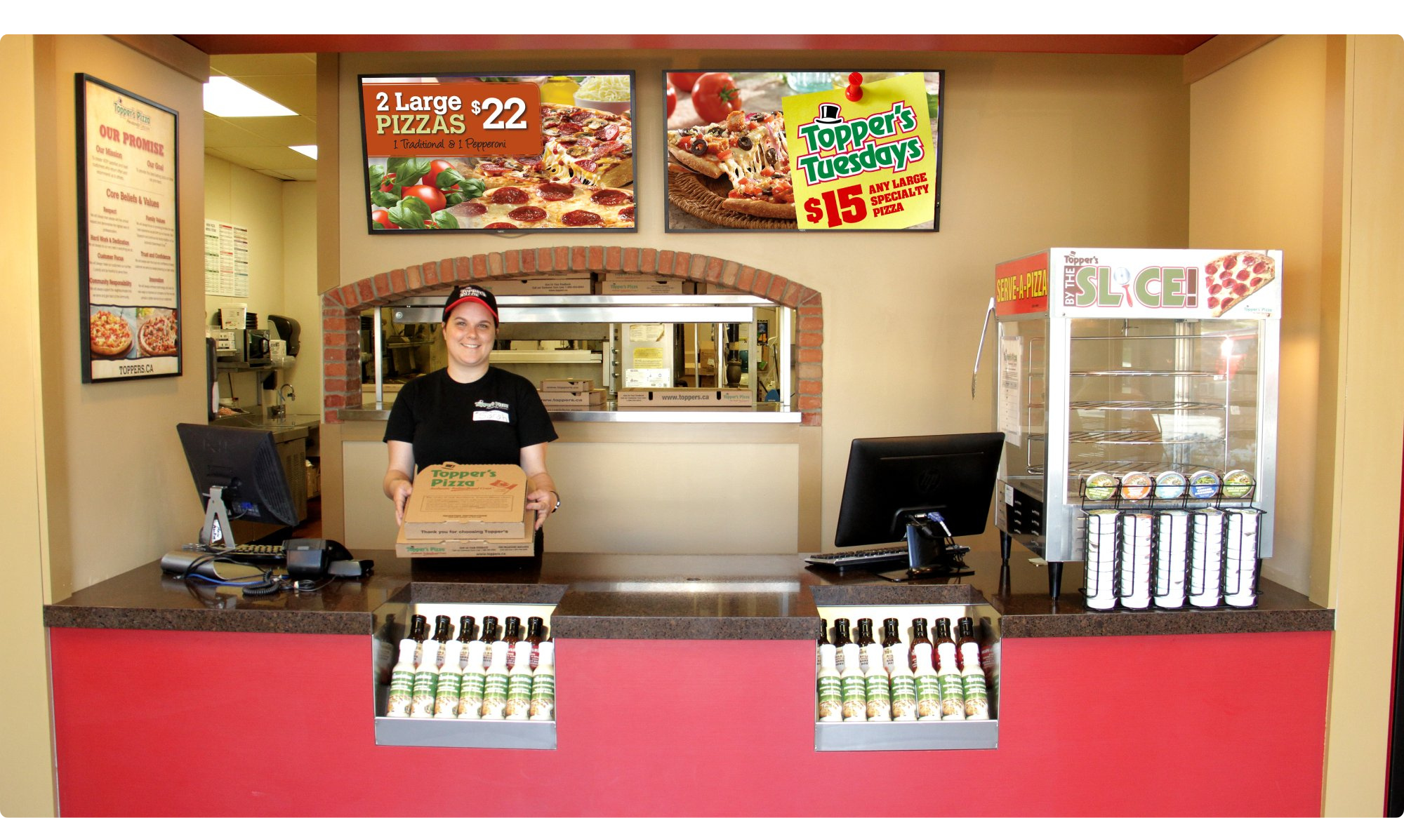 Female employee holding a box of pizza in a pizza shop.