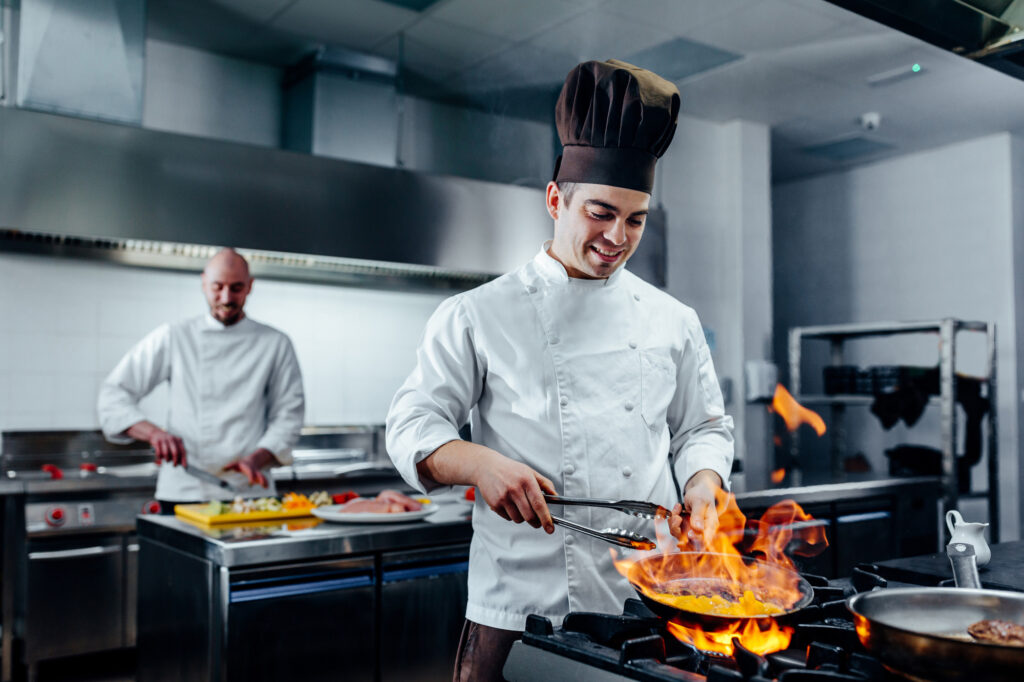 Employee experience in hospitality, foodservice and culinary excellence. Two chefs in white coats cooking in kitchen