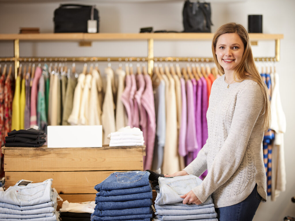 Woman retail employee folding clothes at clothing store.