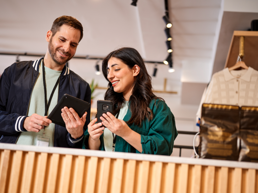 Two retail employees looking at tablet device in clothing store.