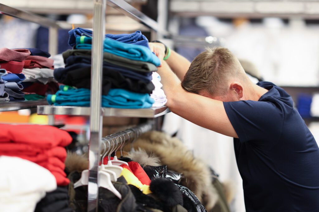 Tired Man Leaned On Shelf With Things In Store