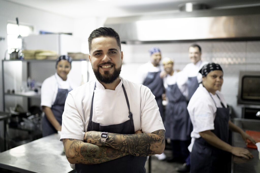 Portrait Of Restaurant Chef With His Team In The Kitchen