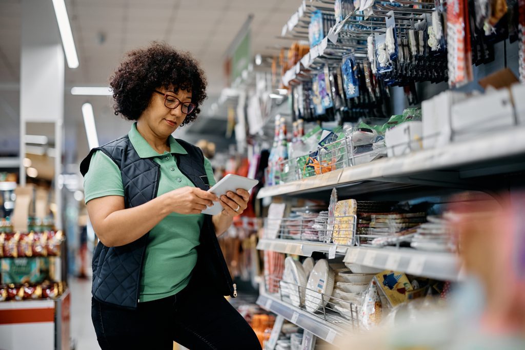 Female Worker Using Digital Tablet While Working At Supermarket.